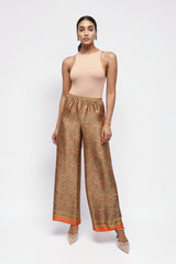Model wearing ALBANA New York apricot silk wide leg pants with a symmetrical paisley print and elastic waistband.