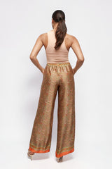 Model wearing ALBANA New York apricot silk wide leg pants with a vibrant paisley print and elastic waistband