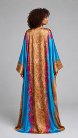 Model wearing an ALBANA New York silk kaftan with a gold leopard print, turquoise panels, and pink floral accents.