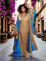 Model wearing an ALBANA New York azure blue and gold satin kaftan with intricate patterns on a cobblestone street.