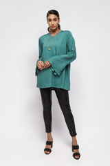 Model wearing ALBANA New York la mer blue textured linen tunic with wide sleeves and high neck paired with black pants