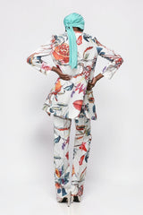 ALBANA New York floral print flare pants and matching jacket worn by a model with a teal headwrap, back view.