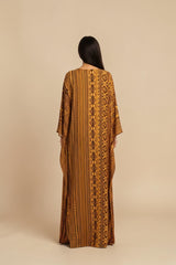 Model wearing ALBANA New York Gilded Amber silk kaftan with tonal geometric patterns and wide sleeves.