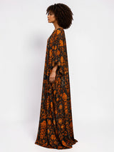 Model wearing an ALBANA New York obsidian silk kaftan with orange heritage-inspired motifs and wide sleeves.