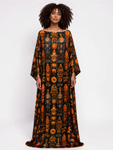 Model wearing an ALBANA New York obsidian silk kaftan with orange heritage-inspired motifs and wide sleeves.