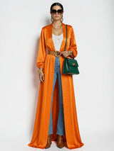 ALBANA New York orange satin maxi duster abaya worn over jeans and a white top with a green handbag
