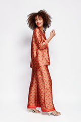 ALBANA New York silk tunic in vibrant red and gold floral print worn by a model with matching wide-leg trousers.