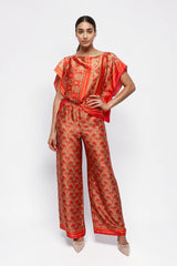Model wearing ALBANA New York Mandarin Scrolls silk wide leg pants and matching top with vibrant red floral patterns