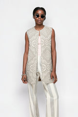 ALBANA New York model wearing beige and white vertical stripe flare pants with a matching patterned sleeveless vest.
