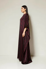 Model wearing an ALBANA New York wine-colored silk kaftan with a boat neckline and flowing, wide-sleeve silhouette.