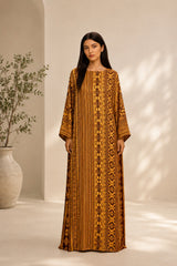Model wearing an ALBANA New York amber silk kaftan with tonal geometric patterns, wide sleeves, and a boat neckline.