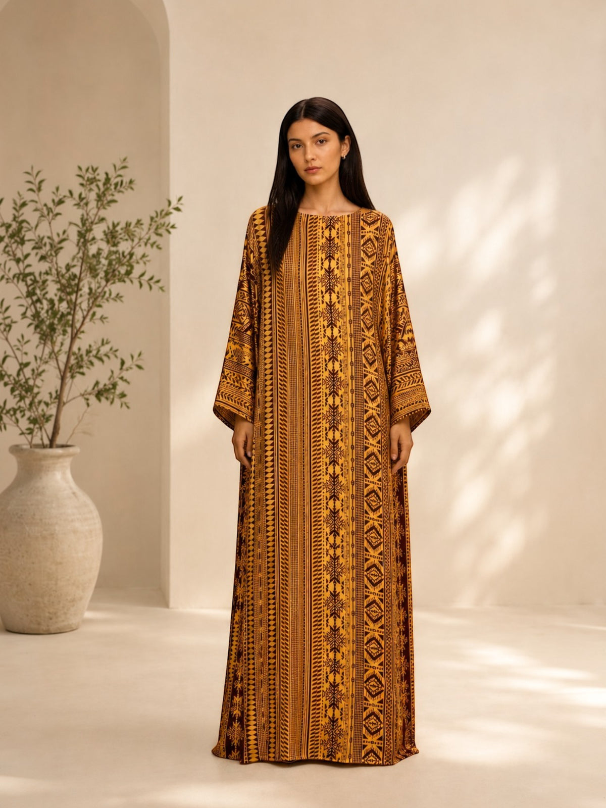 Model wearing an ALBANA New York amber silk kaftan with tonal geometric patterns, wide sleeves, and a boat neckline.