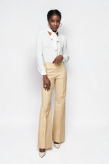 Model wearing ALBANA New York high-waisted beige pinstripe flare trousers with a white blouse against a white background.