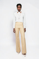 Model wearing ALBANA New York high-waisted beige pinstripe flare trousers with a white blouse and heels.