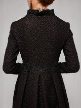 Back view of ALBANA New York black matelassé opera coat with diamond-quilted texture, stand collar, and lace waist detail.