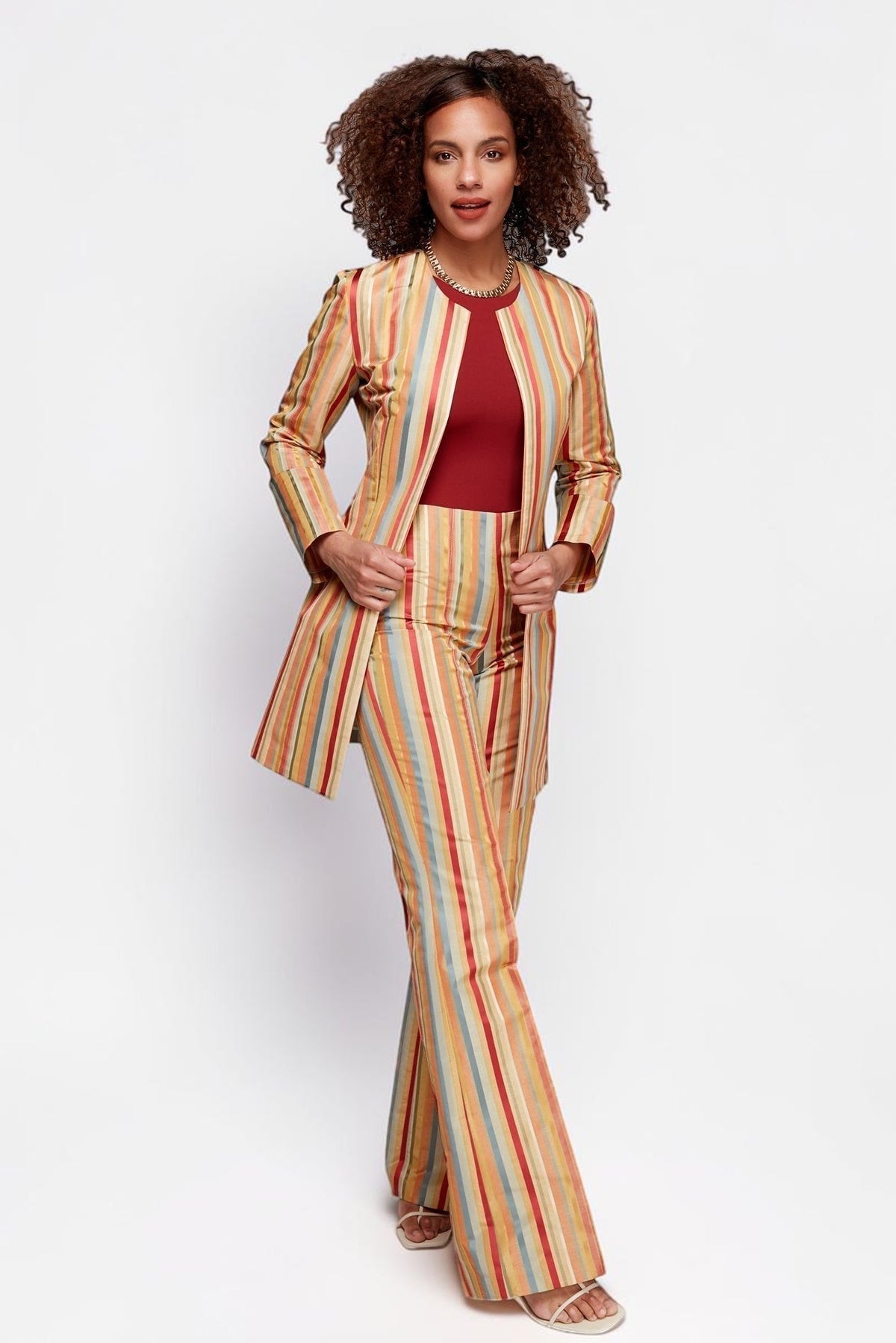 Model wearing ALBANA New York Carousel Stripe Jacket and matching flare pants in multi-coloured vertical stripes