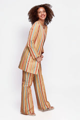 Model wearing ALBANA New York Carousel Stripe Jacket and matching flare pants in a vibrant multi-color stripe pattern.