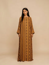 Model wearing an ALBANA New York Gilded Amber silk kaftan with wide sleeves and intricate tonal geometric patterns.