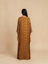Model wearing ALBANA New York Gilded Amber silk kaftan with tonal geometric patterns and wide sleeves.