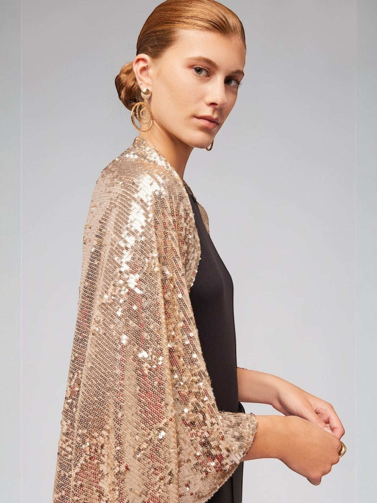 ALBANA New York gold sequin bolero sleeves worn over a black top for an elegant evening look