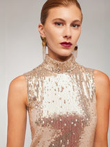 ALBANA New York gold sequin sleeveless blouse with a mock neck worn by a model with statement earrings