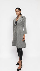 Model wearing an ALBANA New York grey plaid longline blazer coat with a lapel collar and button-front closure.