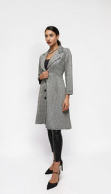 Model wearing an ALBANA New York grey plaid longline blazer coat with a lapel collar and button-front closure.