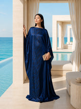 Model wearing an ALBANA New York Midnight Nocturne silk kaftan in midnight blue with wide sleeves by a luxury pool.