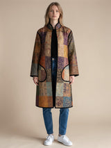 Model wearing ALBANA New York longline silk coat with mosaic pattern, noir trim, and functional front pockets.