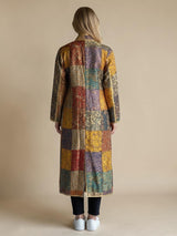 Back view of a woman wearing an ALBANA New York long silk coat with a colorful mosaic pattern and gold trim.