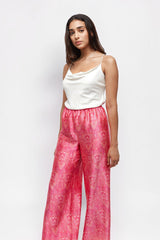 Model wearing ALBANA New York rose pink silk wide leg pants with a vibrant paisley print and elastic waistband.