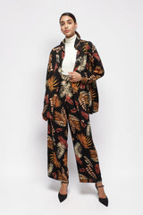 Model wearing ALBANA New York printed foliage crepe shirt and matching wide leg pants in black, orange, and cream.