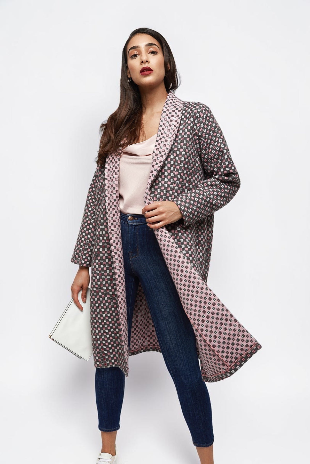 Model wearing an ALBANA New York longline open-front coat with a geometric print and contrasting pink inner lining.