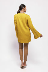 ALBANA New York saffron yellow textured linen tunic with high neck and wide bell sleeves worn by a model from behind
