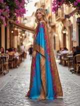 Model wearing an ALBANA New York satin kaftan with gold leopard print and vibrant turquoise floral panels on a street