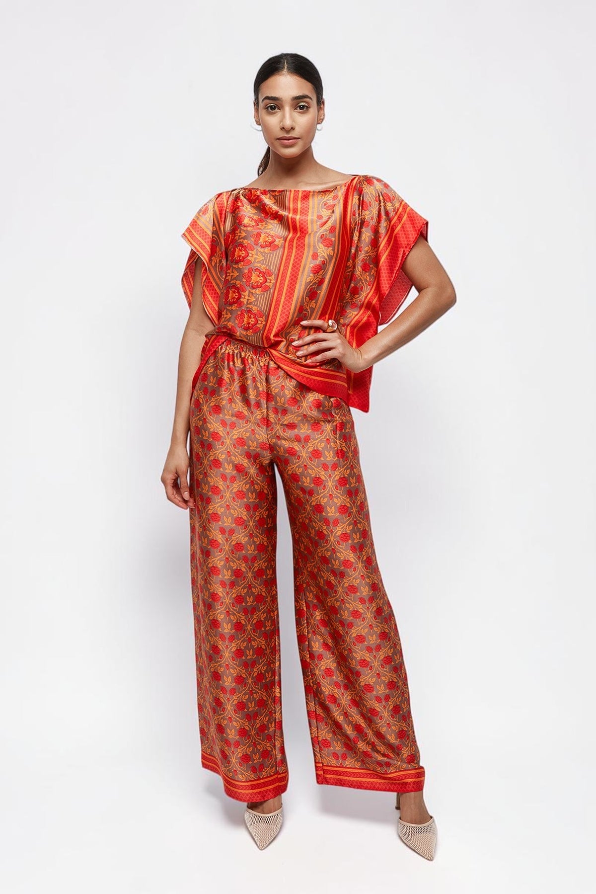 Model wearing ALBANA New York Mandarin Scrolls silk wide leg pants and matching top with vibrant red floral patterns