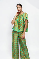 Model wearing ALBANA New York Sage Scrolls silk wide leg pants and matching green patterned silk top