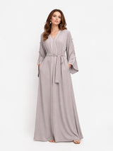 Model wearing ALBANA New York Stone Veil maxi kaftan in stone grey with long sleeves, waist tie, and elegant drape.