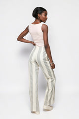 Model wearing ALBANA New York mid-rise cotton flare pants with vertical grey and cream stripes, back view.
